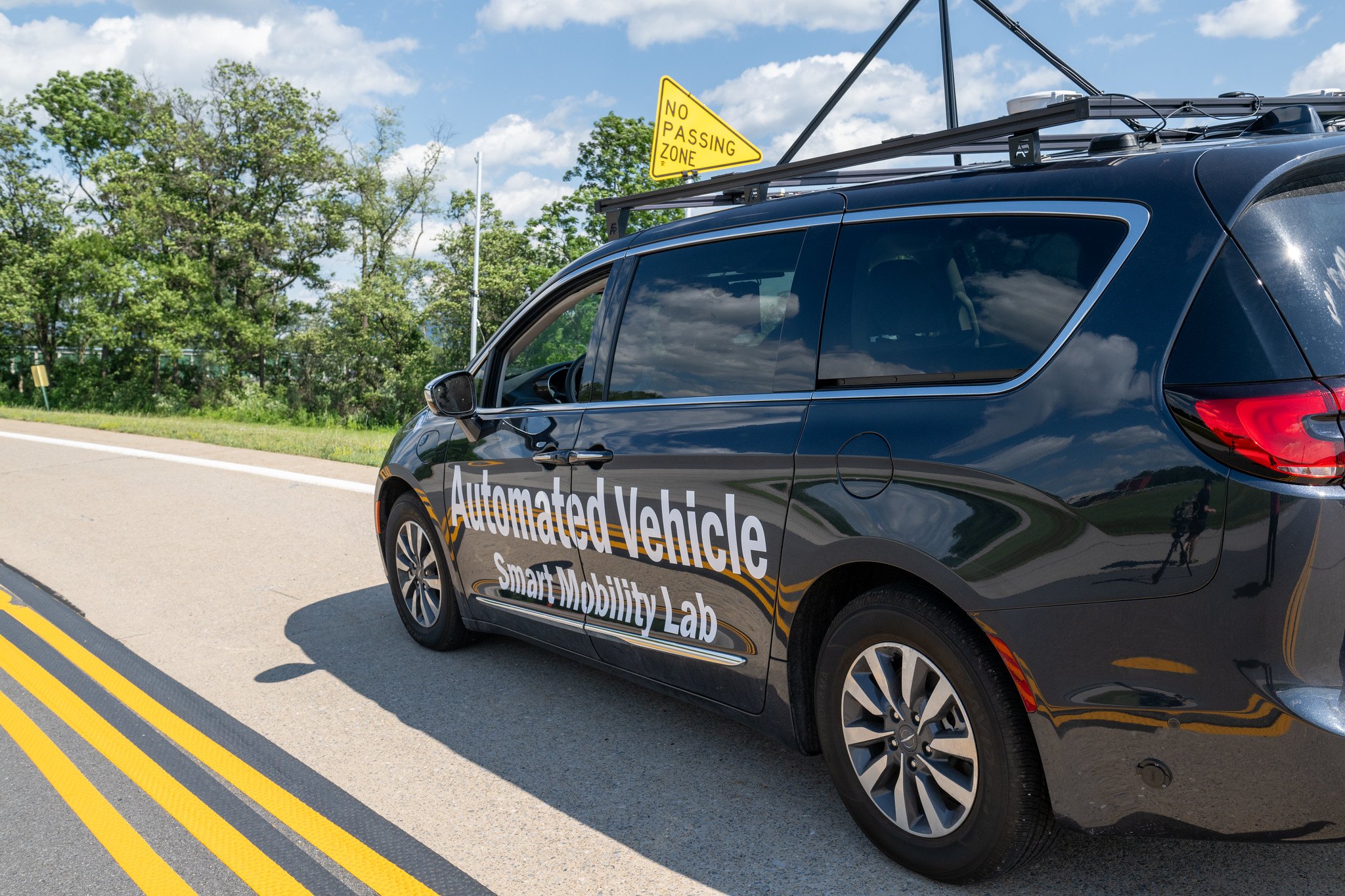 The lab's wrapped automated vehicle on the LTI test track beside a no-passing-zone sign